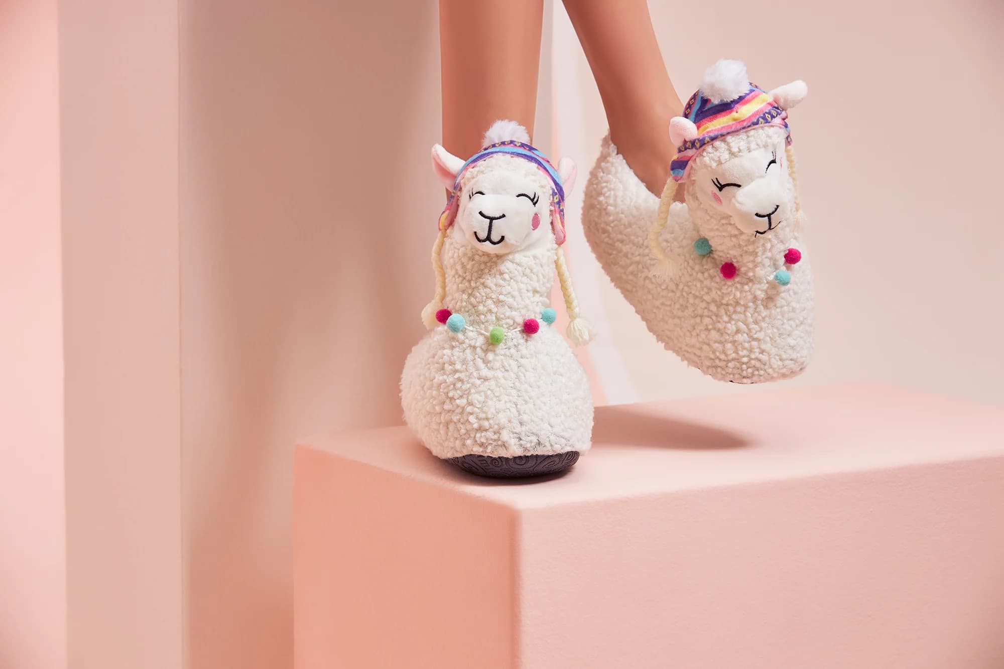 Peluş figürlü ev terlikleri, pembe kaide üzerinde